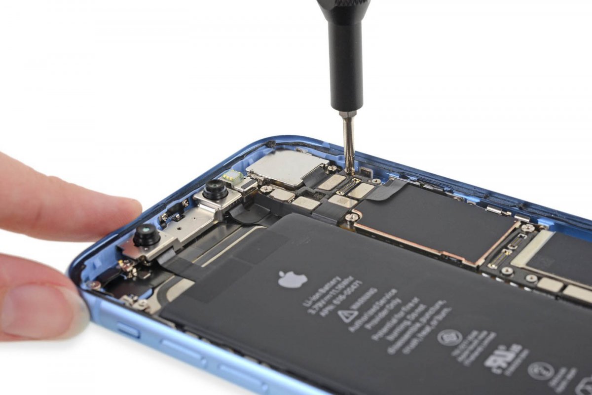 An open iPhone Xr being repaired with a screwdriver
