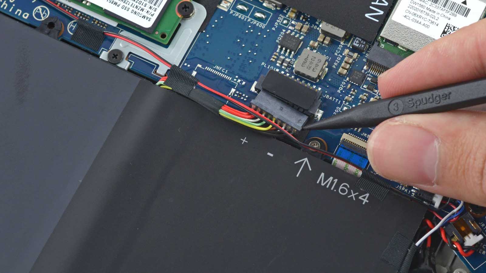 A spudger unplugging the battery of a Dell XPS 13 laptop.