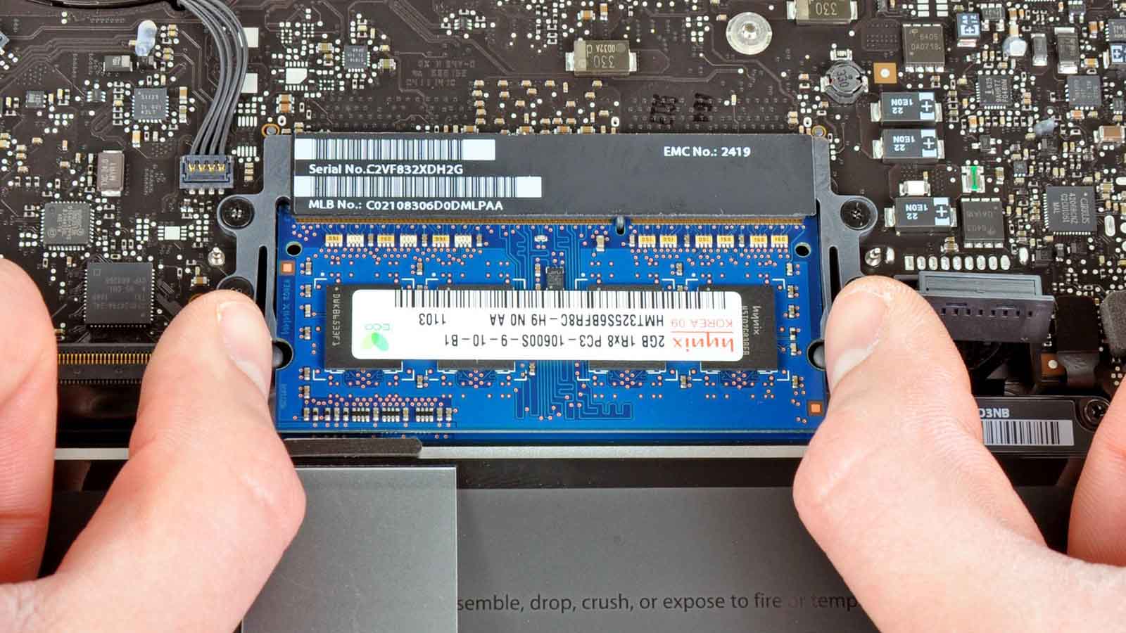 Two hands removing the RAM of a 2012-era MacBook.