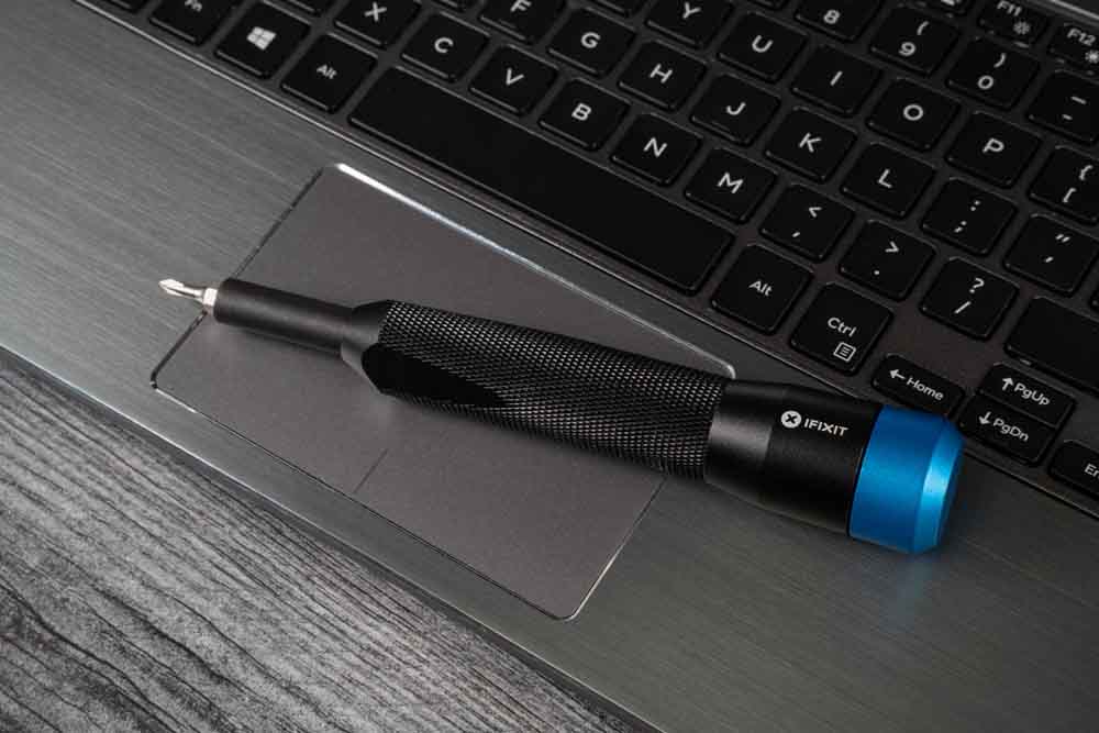 An iFixit screwdriver sitting on a laptop.