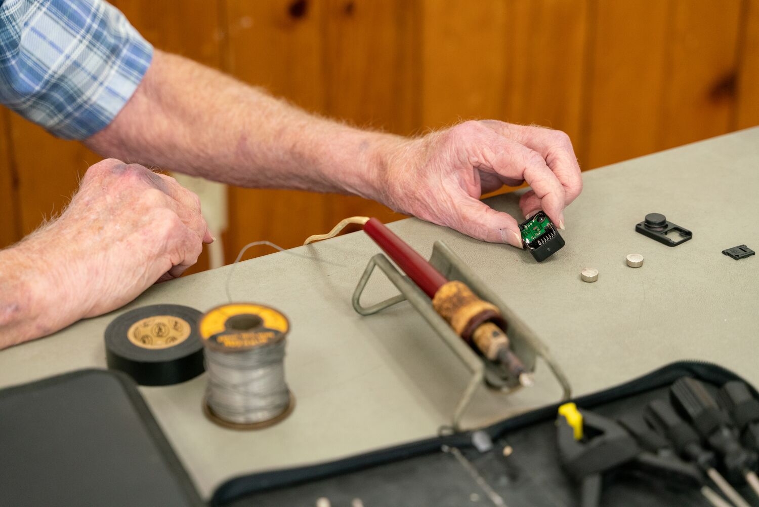 Man's hands holding a small electrical component at a repair cafe.