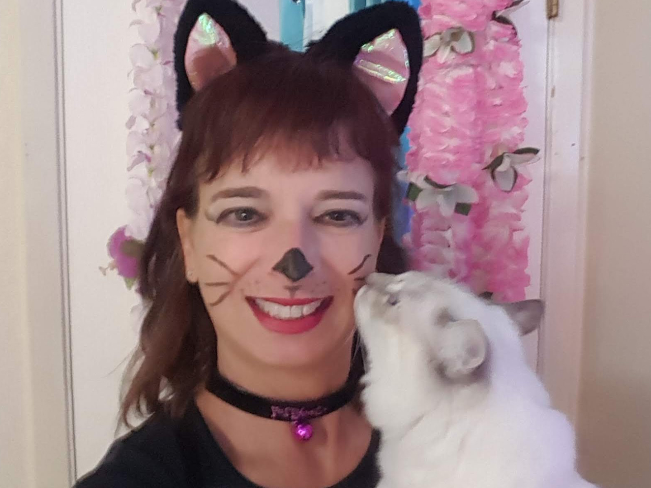 Cynthia in a cat costume, holding a cat.