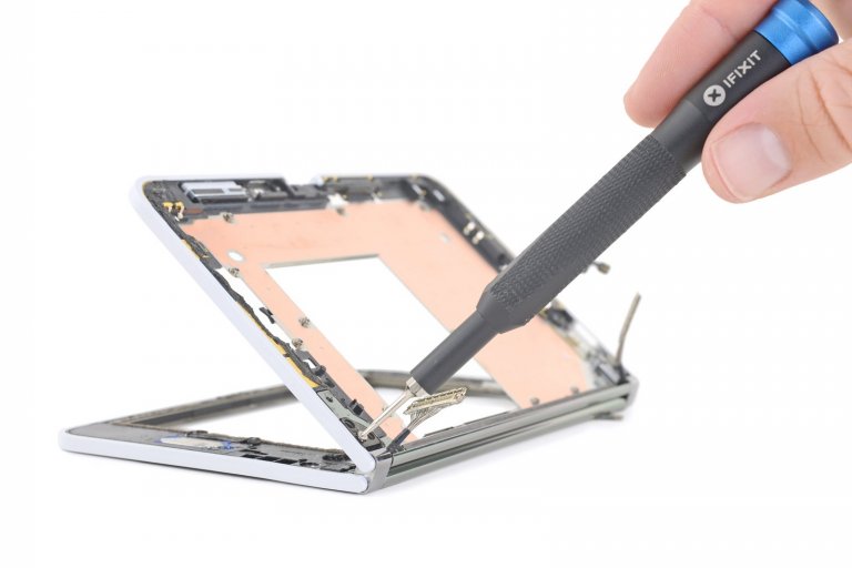 iFixit screwdriver removing a hinge screw from Microsoft Surface Duo
