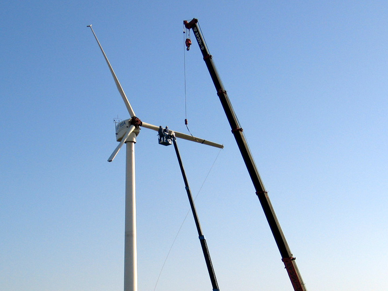 Workers repair a broken wind turbine via cranes