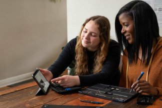 Two women repair a MacBook