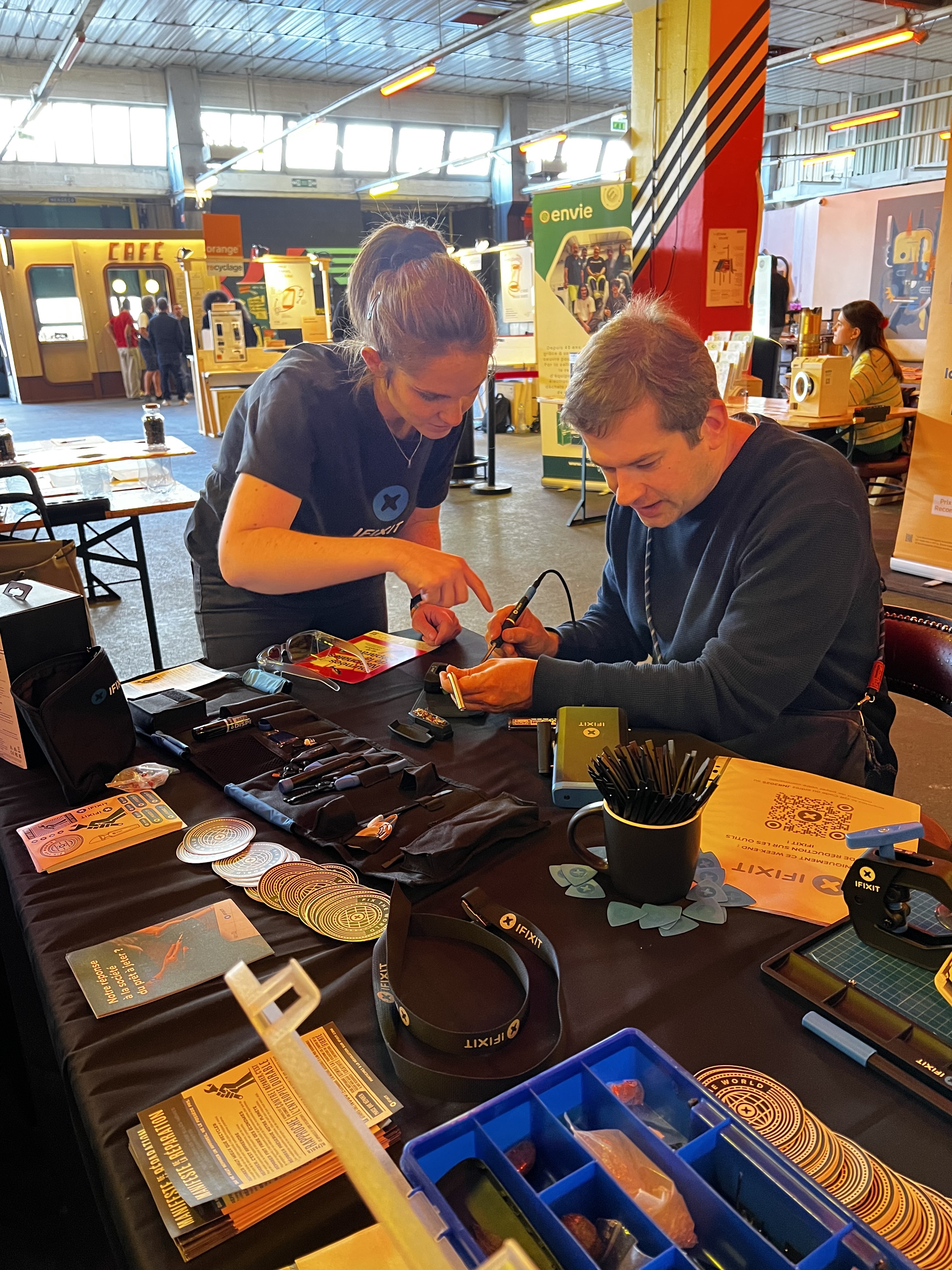 An iFixit employee explaining a visitor how to solder at JNR Paris 2025